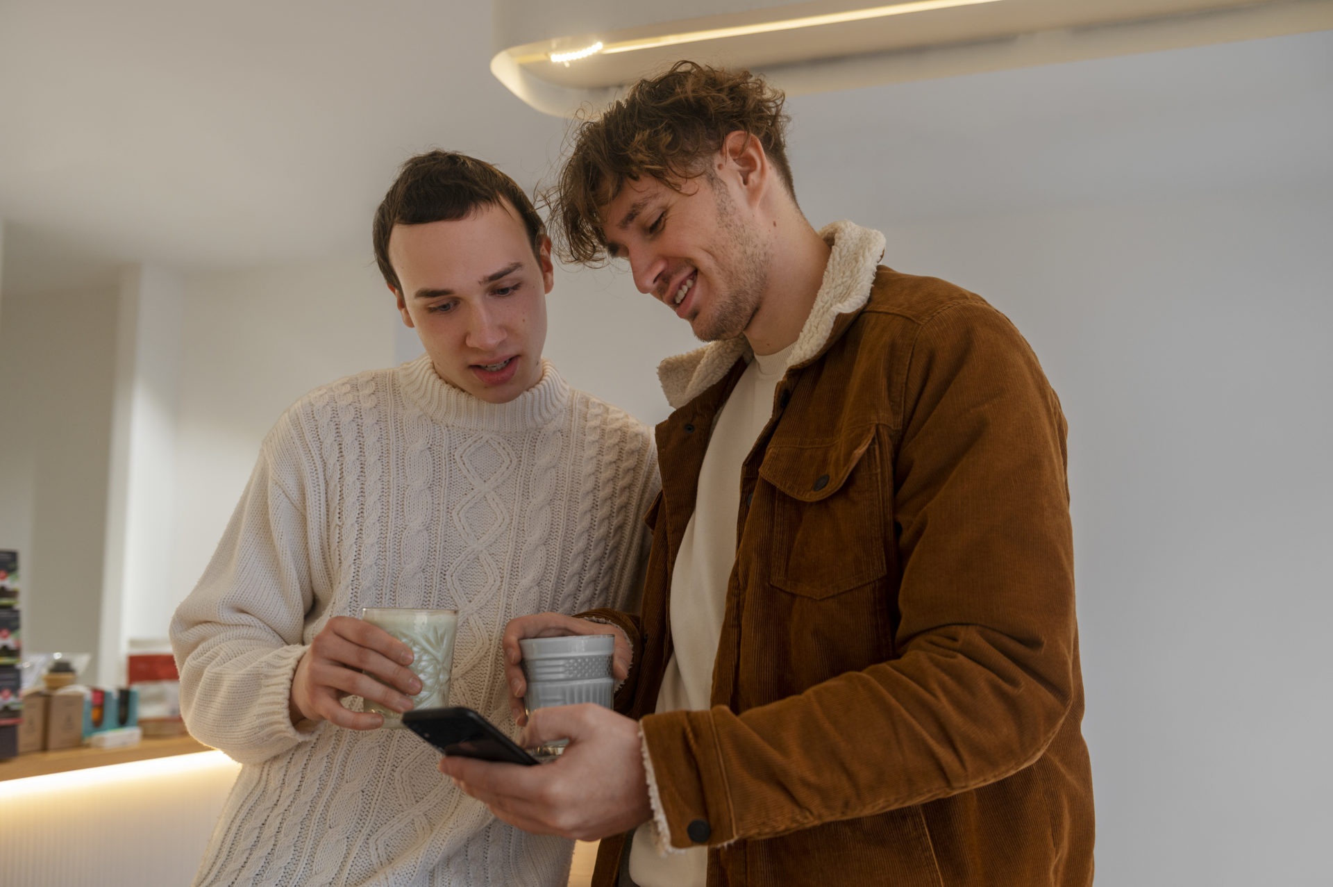 Deux hommes en train de regarder un téléphone.